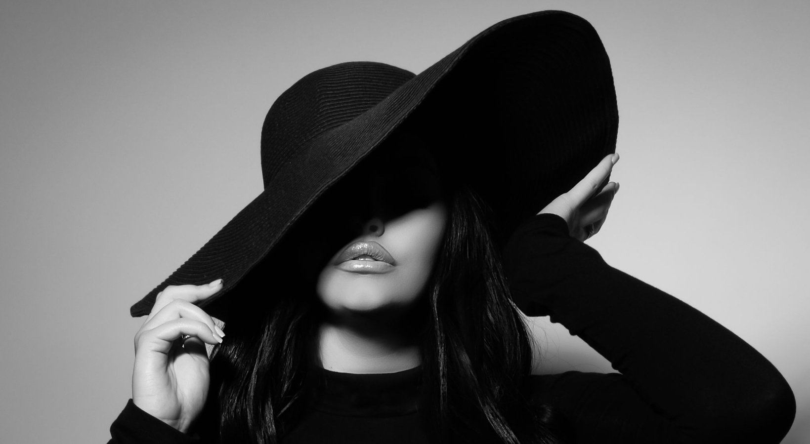 the is the perfect artist shot of a girl with the most perfect lips posed with a hat covering one eye in a dramatic lighting pose looking very elegant taken in Modestos most exclusive photography studio by the best photographer in California 