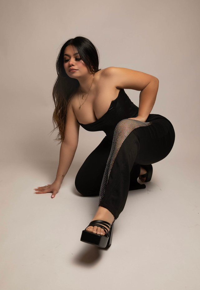 30th birthday photoshoot taken in the downtown modesto photography studio by aly incardona wearing a black corset and black pants with diamond fishnet across the knee in a crouched down dramatic artistic pose 