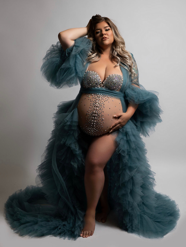 a mother wearing a dusty blue tulle robe and a jewel bodysuit that complimented this maternity photoshoot so well. Her dramatic pose and sultry look on her face was perfectly taken by a private Modesto studio by a talented artist 