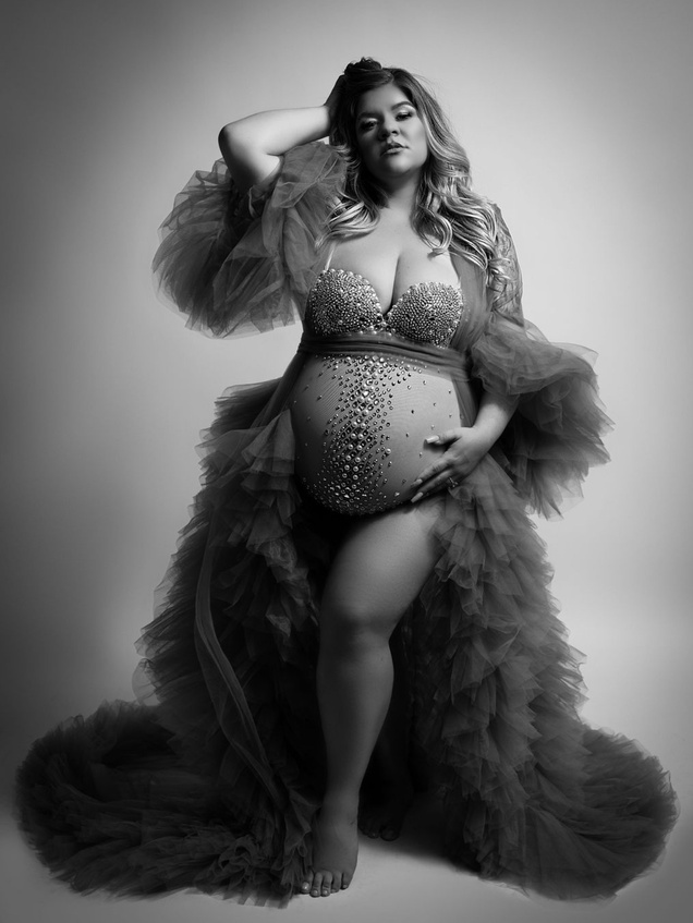 a monochrome version of mother wearing a dusty blue tulle robe and an ARBackdrops jewel bodysuit that complimented this maternity photoshoot so well. Her dramatic pose and sultry look on her face was perfectly taken by a private Modesto studio 