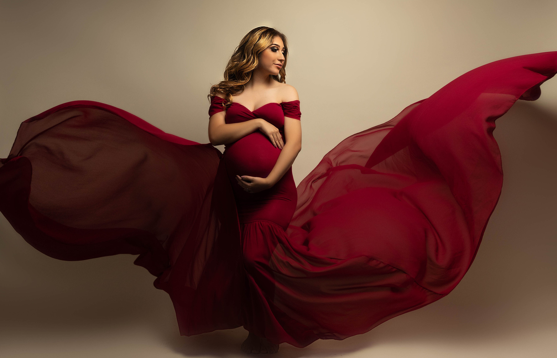 red flowing maternity dress with swoop sleeves and a tulle double tossing train. This pregnancy portrait was taken in the studio by Aly Incardona who was voted the best photographer in the Central Valley modesto California 